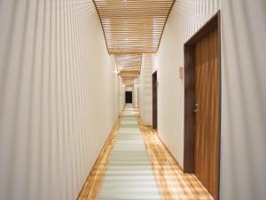 a long corridor with white walls and a long hallway at Hakuba Ryujin Onsen in Hakuba