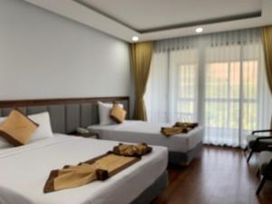um quarto de hotel com duas camas e uma janela em Bờ Biển Vàng Hotel em Ke Ga