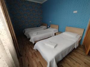three beds in a room with blue walls and wooden floors at Hostel Kutaisi by Kote in Kutaisi