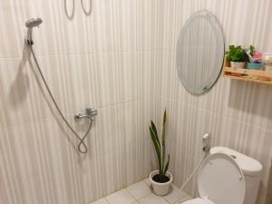 een badkamer met een toilet en een spiegel en een plant bij JnJ Homestay in Timuran