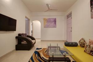 a living room with a yellow couch and a tv at Rahul Service Apartment in Calangute