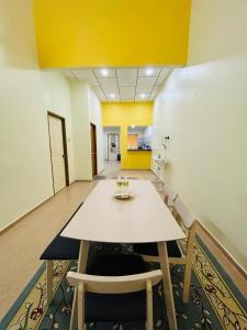 a table and chairs in a room with a yellow ceiling at Sena Yang Indah Homestay in Kangar