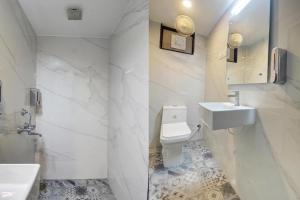 a white bathroom with a sink and a toilet at Rahul Service Apartment in Calangute