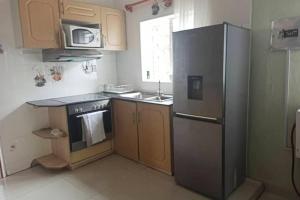 een keuken met een roestvrijstalen koelkast en een wastafel bij Nichi's Guesthouse - Cosy 3 bedroom with breakfast in Blantyre