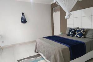 a bedroom with a bed with blue and white pillows at Nichi's Guesthouse - Cosy 3 bedroom with breakfast in Blantyre