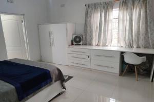 een slaapkamer met een bed, een bureau en een raam bij Nichi's Guesthouse - Cosy 3 bedroom with breakfast in Blantyre