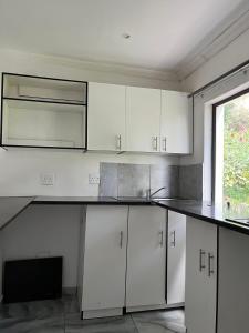 a kitchen with white cabinets and a black counter top at Goshen in Johannesburg