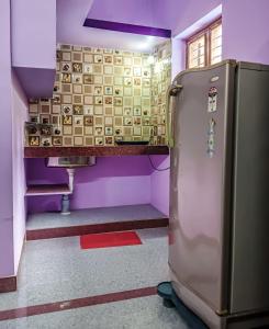 a kitchen with a refrigerator in a room with purple walls at NAKSHATHRA Guest House 2BHK in Tiruvannāmalai