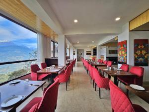 a restaurant with tables and red chairs and a large window at Sumitel Pelling in Pelling