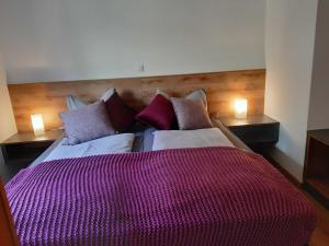Un dormitorio con una cama grande con sábanas y almohadas púrpuras. en Ferienwohnungen Handwerger en Hollfeld