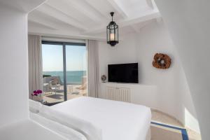 a white room with a bed and a television at Anantara Santorini Abu Dhabi Retreat-Adults Only in Al Rahba