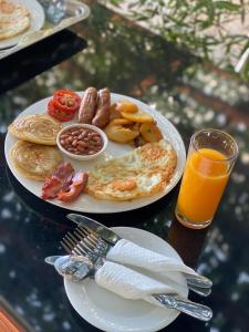 een bord met ontbijtproducten en een glas sinaasappelsap bij Lake Elementaita Manor in Gilgil