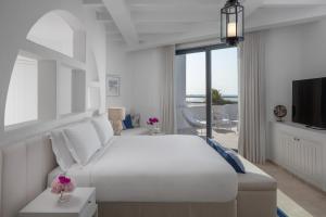 a white bedroom with a large bed and a television at Anantara Santorini Abu Dhabi Retreat-Adults Only in Al Rahba