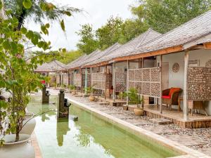 una fila de casas junto a un charco de agua en BUNGALOW CAFE GILI BEACH FRONT en Gili Meno