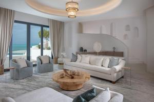 uma sala de estar com um sofá, cadeiras e uma mesa em Anantara Santorini Abu Dhabi Retreat-Adults Only em Al Rahba
