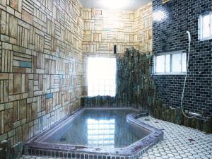 a bathroom with a tub with a tile wall at Kanko Ryokan Yamato in Ikuma