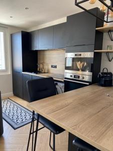 a kitchen with a wooden table and black cabinets at Appartement moderne avec garage et accès métro à 100m in Villeurbanne