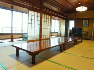een houten tafel in een kamer met ramen bij Kanko Ryokan Yamato in Ikuma
