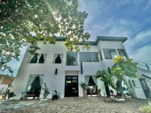 a white house with a courtyard in front of it at Evergreen Homestay in Phan Thiet