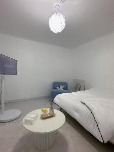 a white bedroom with a bed and a table and a light at Jeongdam in Seoul