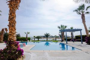 a pool at a resort with palm trees and purple flowers at El Gouna Elite Worldwide Private Residences, Sea & Garden View - Hurghada, Egypt in Hurghada