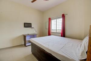 a bedroom with a large bed and a window at SPOT ON Eastsons' Guest House & Cafe in Rāmnagar