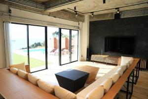 Una gran sala de estar con un sofá grande y un televisor. en Moroisoso モロイソソウ 大型温水プール付 高級貸切ヴィラ BBQ＆プライベートビーチ, en Miura
