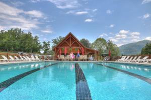 ein großer Pool mit einem Holzgebäude mit Stühlen in der Unterkunft Ali's Dream cabin in Sevierville