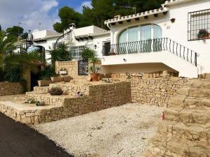 a large white house with a stone wall at Charming 3 bedroom villa located in Moraira. in Teulada