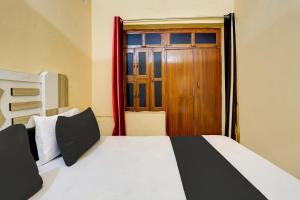 a bedroom with a bed and a wooden door at OYO Flagship Hotel Suraj Villa in Nārnaul