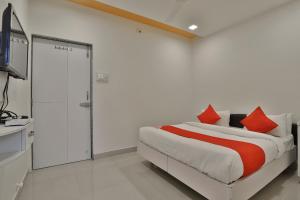 um quarto com uma cama com almofadas vermelhas em OYO Hotel Balaji Inn em Hālol