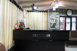 a reception desk in a room with a clock on the wall at The Apsara in Rājahmundry