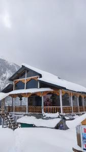 a building covered in snow with mountains in the background at Devropa Heights in Malāna
