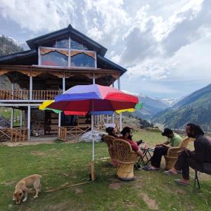 a group of people sitting under an umbrella in front of a house at Devropa Heights in Malāna