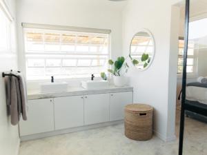 a white bathroom with two sinks and a window at Middelpunt Branch in Robertson