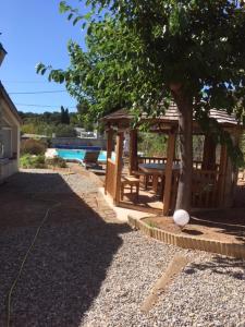 a wooden gazebo with a tree next to a pool at Joli pavillon individuel in Carry-le-Rouet