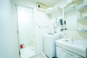 a white bathroom with a shower and a sink at Smart Vacation Canaan A スマートバケーション　カナン A in Kagoshima