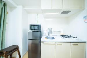 a small kitchen with a refrigerator and a sink at Smart Vacation Canaan A スマートバケーション　カナン A in Kagoshima