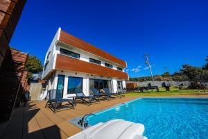 una casa con piscina al lado de un edificio en Moroisoso モロイソソウ 大型温水プール付 高級貸切ヴィラ BBQ＆プライベートビーチ, en Miura