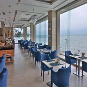 a dining room with blue chairs and tables and the ocean at Anemon Ordu in Ordu