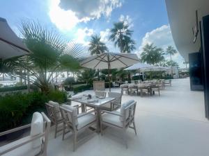 patio ze stołami, białymi krzesłami i parasolami w obiekcie Beachfront Haven w Dubaju