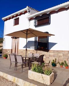 un patio con mesa, sillas y sombrilla en Alojamiento vacacional Loma Alta, en Cambil