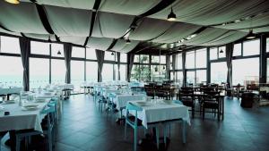 シアジクにあるMaya Bistro Hotel & Beachの白いテーブルと椅子、窓のあるレストラン