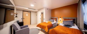 a hotel room with two beds and a chair at Hotelli Visiitti in Ylivieska +24 photos