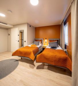 two beds in a room with orange walls at Hotelli Visiitti in Ylivieska