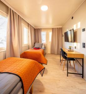Habitación con 2 camas, escritorio y mesa. en Hotelli Visiitti en Ylivieska