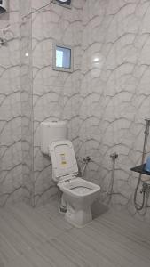 een badkamer met een toilet en een stenen muur bij Raj Darbar Hotel in Goddā