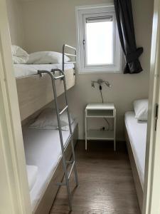 a small room with two bunk beds and a window at Meerchalet in Biggekerke