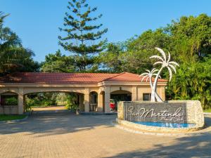 un cartello di fronte a un edificio con una palma di San Martinho Beach Club a Vila Praia Do Bilene Altre 34 foto