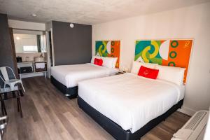 two beds in a hotel room with red pillows at Developer Inn Express Fundamental, a Travelodge by Wyndham in Kissimmee